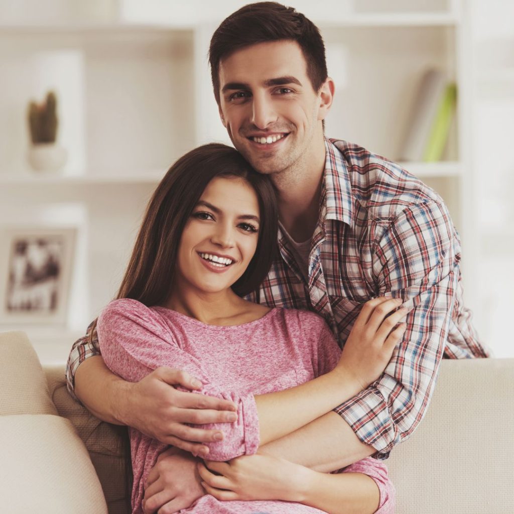 Happy couple embracing on a couch, smiling, representing support and well-being in relation to food intolerance testing services.